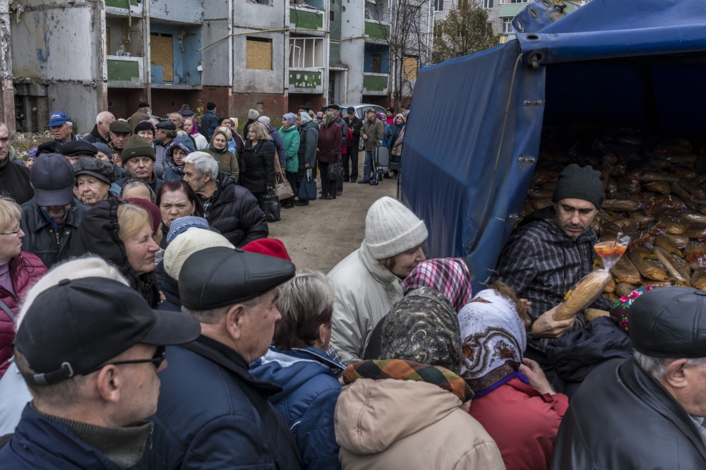 People in line for loaves of bread provided by the United Nations by high-rise residence buildings in Chernihiv, Ukraine, Oct. 19, 2022. (Brendan Hoffman/The New York Times)