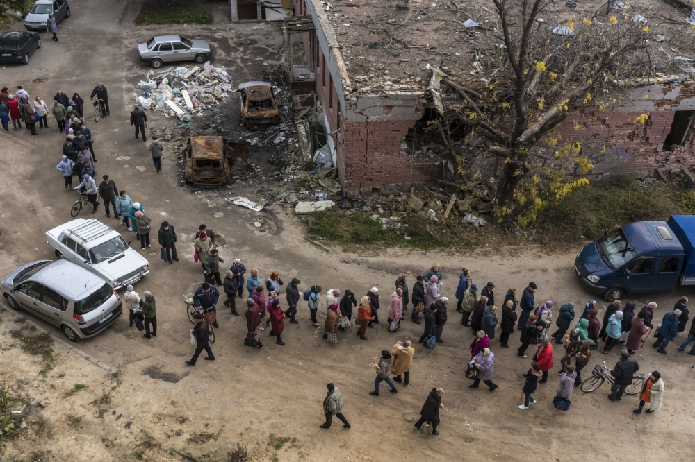 People in line for loaves of bread provided by the United Nations by high-rise residence buildings in Chernihiv, Ukraine, Oct. 19, 2022. (Brendan Hoffman/The New York Times)