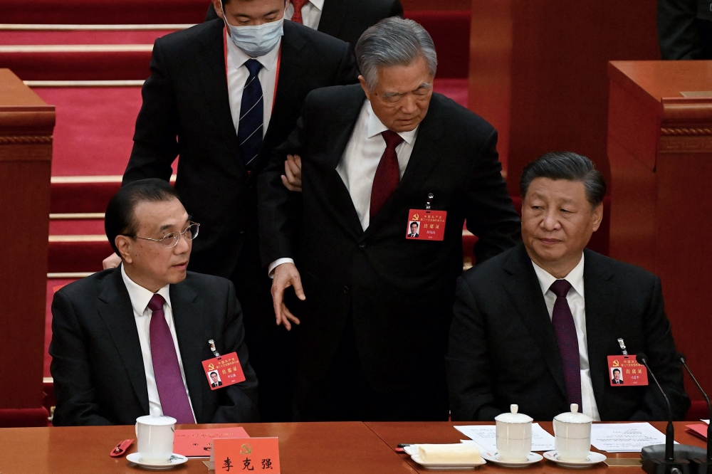 China's President Xi Jinping (R) sits besides Premier Li Keqiang (L) as former president Hu Jintao (C) is assisted to leave from the closing ceremony of the 20th China's Communist Party's Congress at the Great Hall of the People in Beijing on October 22, 2022. (Photo by Noel Celis / AFP)