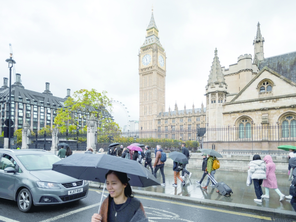 People walk past the Houses of Parliament in Westminster, London.