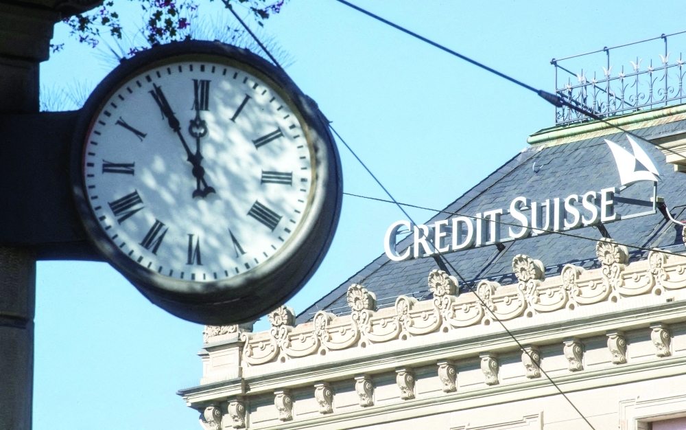 A clock is seen near the logo of Swiss bank Credit Suisse at the Paradeplatz square in Zurich. -- Reuters