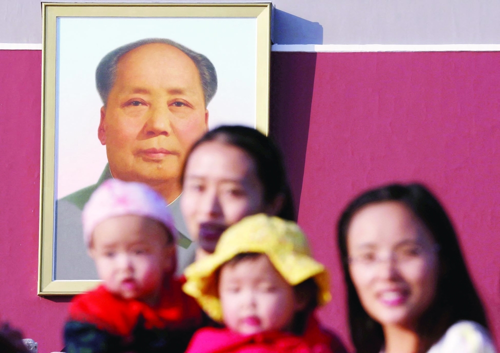 Two women and their babies pose for photographs in front of the giant portrait of late Chinese chairman Mao Zedong on the Tiananmen Gate in Beijing. - Reuters file photo