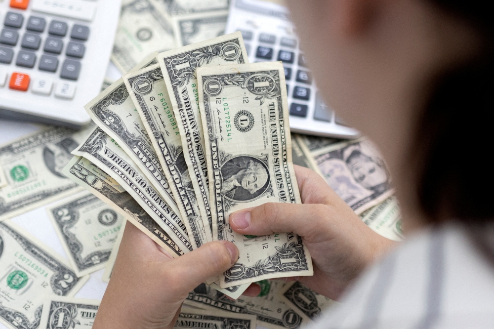 Woman holds U.S. dollar banknotes in this illustration taken May 30, 2022.