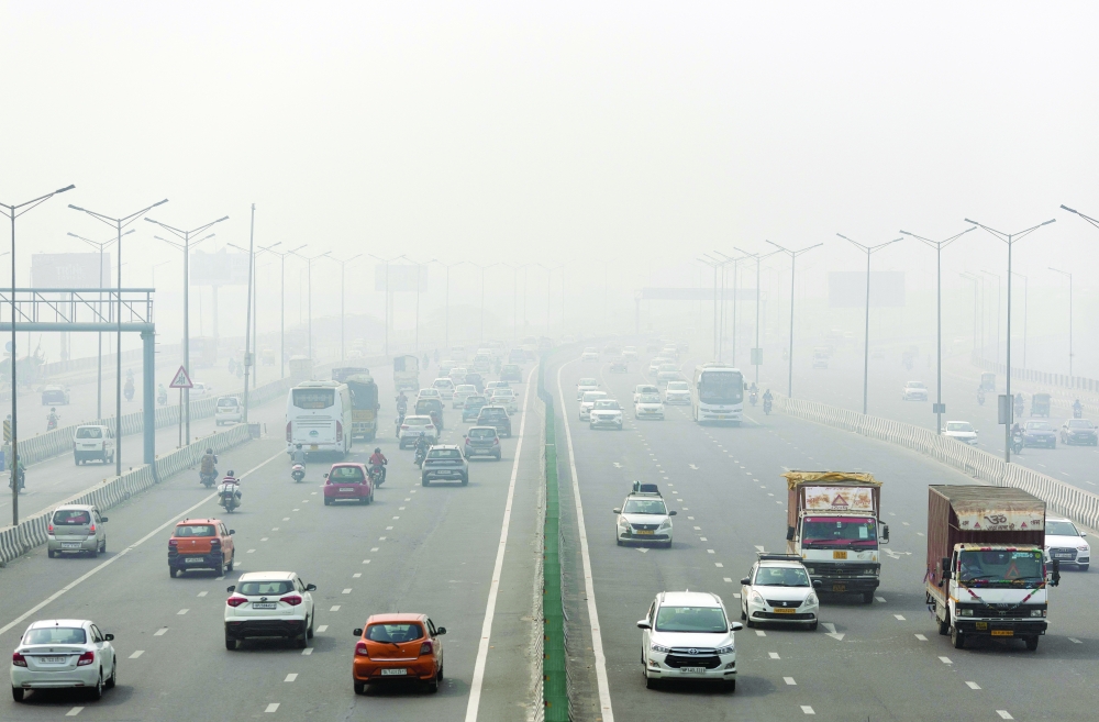 Traffic moves along a highway shrouded in heavy smog in New Delhi on Thursday. -- Reuters
