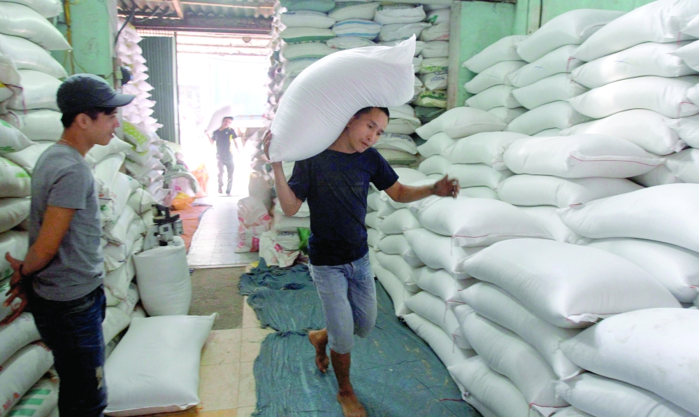 A worker carries a bag of rice to a store outside Hanoi. Global food prices have been falling since hitting an all-time high in March. -- Reuters