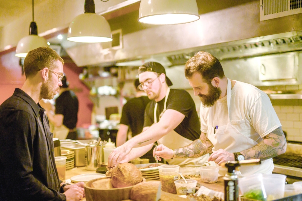 Chase Sinzer, left, and Joshua Pinsky, right, owners of Claud, prepare plates with Kai Christensen at the restaurant in New York, Oct. 27, 2022. (Daniel Krieger/The New York Times)