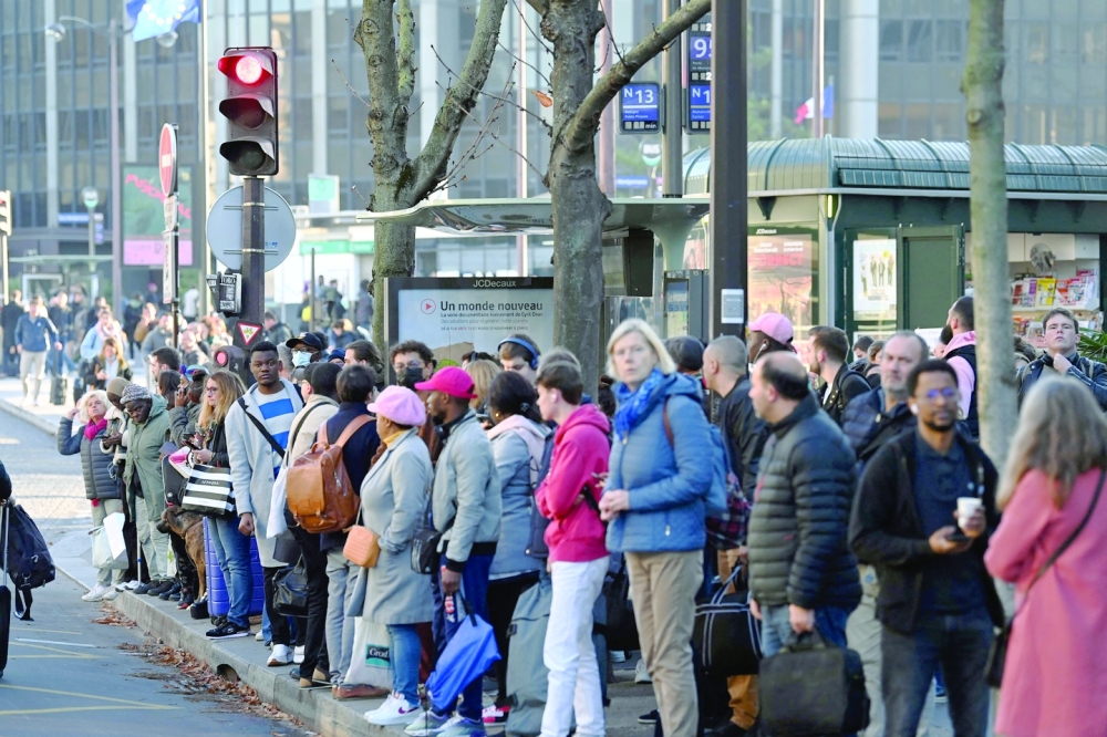 Commuters wait for the buses near Montparnasse train station in Paris during a strike on Thursday. -- AFP 