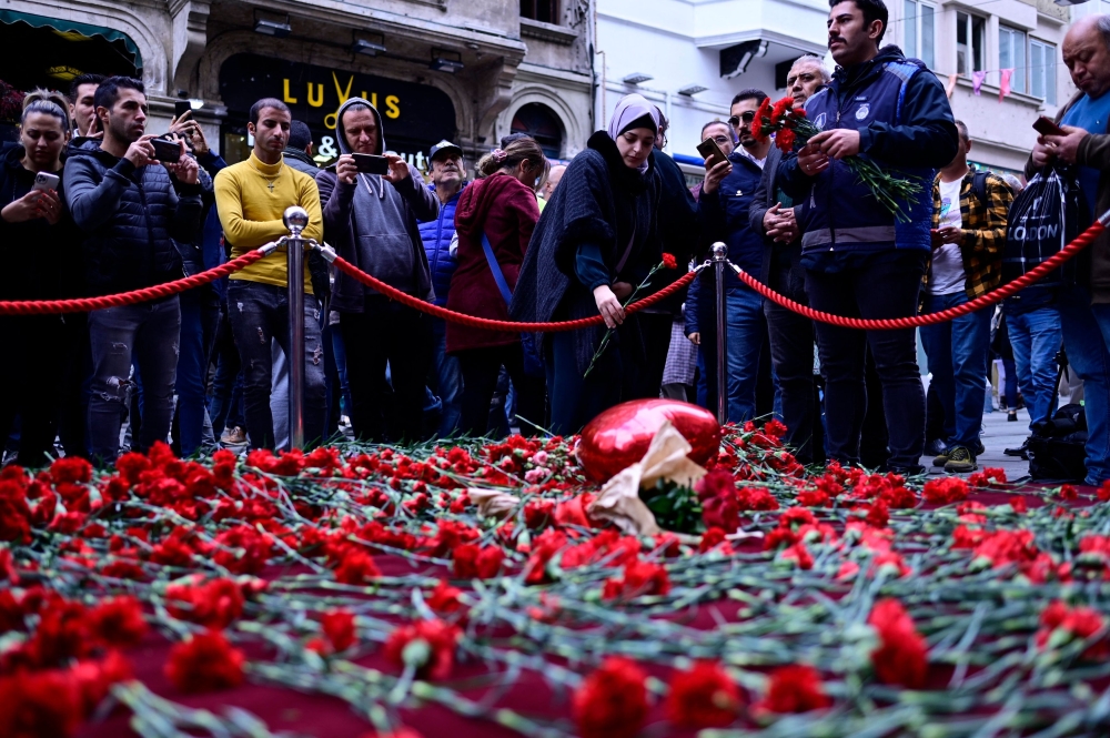 People lay flowers at a makeshift memorial for the victims of November 13 explosion at the busy shopping street of Istiklal in Istanbul on November 14, 2022.