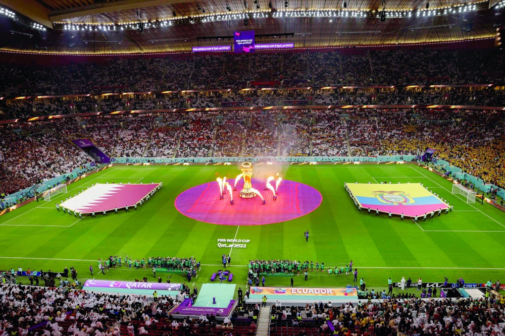 TOPSHOT - A FIFA World Cup trophy replica is pictured on the pitch as fireworks go off ahead of the Qatar 2022 World Cup Group A football match between Qatar and Ecuador at the Al-Bayt Stadium in Al Khor, north of Doha on November 20, 2022.  (Photo by Odd ANDERSEN / AFP)

