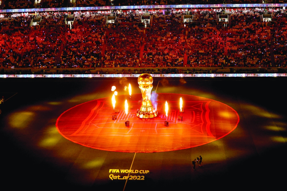 TOPSHOT - A FIFA World Cup trophy replica is pictured on the pitch as fireworks go off ahead of the Qatar 2022 World Cup Group A football match between Qatar and Ecuador at the Al-Bayt Stadium in Al Khor, north of Doha on November 20, 2022.  (Photo by Odd ANDERSEN / AFP)

