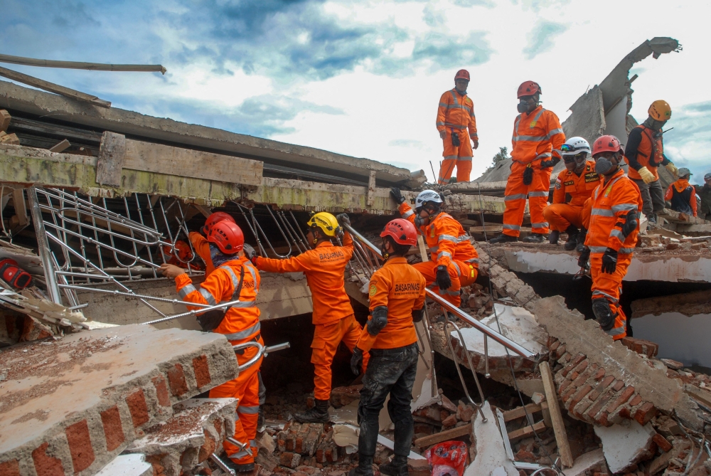 Rescue workers look for victims under the ruins of collapsed buildings in Cianjur on November 22, 2022, following a 5.6-magnitude earthquake that killed at least 162 people, with hundreds injured and others missing.