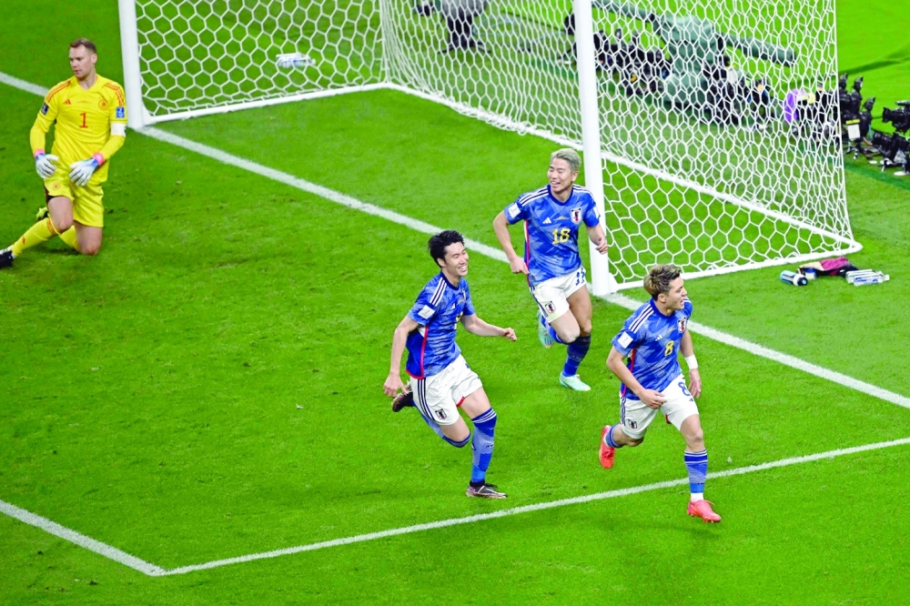 Japan's midfielder #08 Ritsu Doan (R) celebrates scoring his team's first goal during the Qatar 2022 World Cup Group E football match between Germany and Japan at the Khalifa International Stadium in Doha on November 23, 2022. (Photo by Anne-Christine POUJOULAT / AFP)

