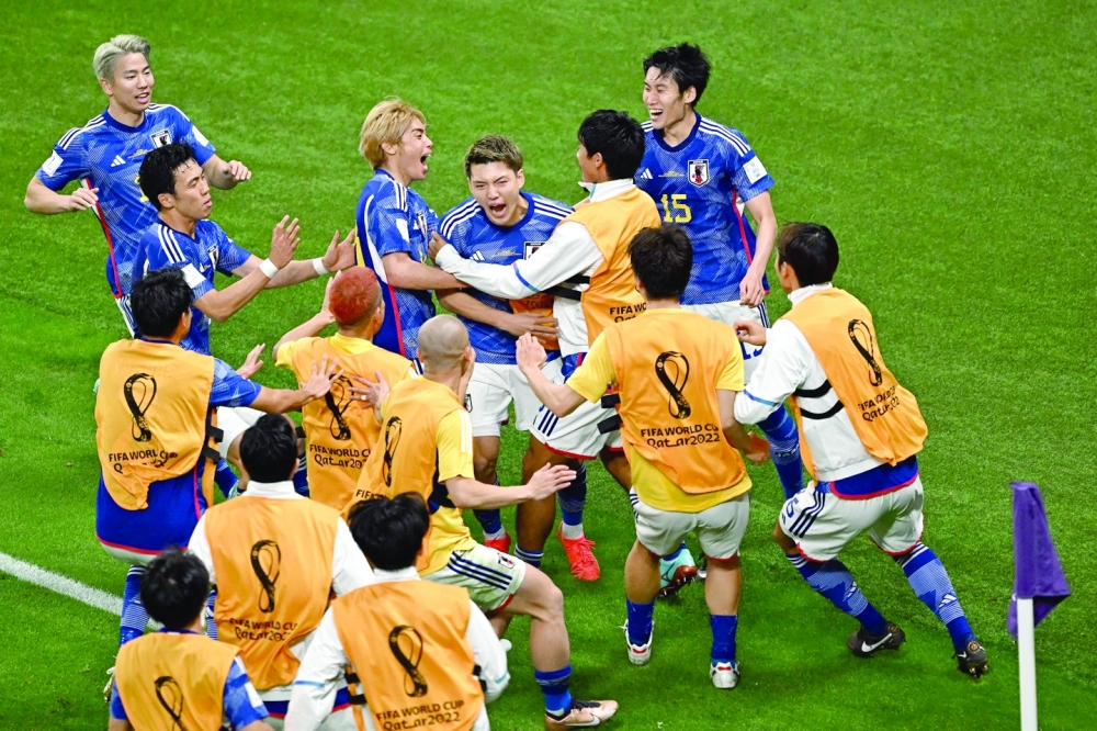 TOPSHOT - Japan's midfielder #08 Ritsu Doan (C) celebrates with teammates after scoring his team's first foal during the Qatar 2022 World Cup Group E football match between Germany and Japan at the Khalifa International Stadium in Doha on November 23, 2022. (Photo by Anne-Christine POUJOULAT / AFP)

