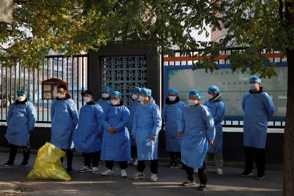 Epidemic prevention workers in protective aprons stand outside a locked-down residential compound as outbreaks of the coronavirus disease (COVID-19) continue in Beijing, November 23, 2022. 