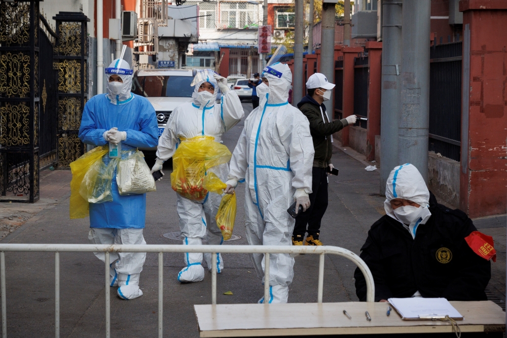 Epidemic prevention workers in protective suits walk in a locked-down residential compound as outbreaks of the coronavirus disease (COVID-19) continue in Beijing, November 23, 2022. 