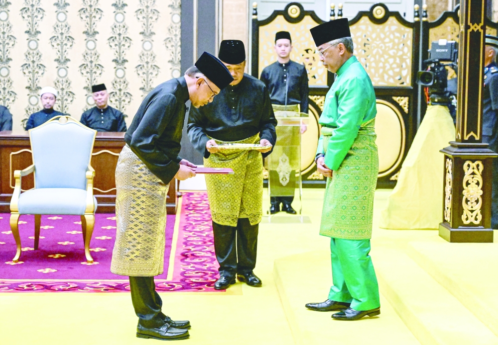 Malaysia's King Al-Sultan Abdullah (R) and Malaysia's newly appointed Prime Minister Anwar Ibrahim take part in the swearing-in ceremony at the National Palace in Kuala Lumpur, Malaysia, on Thursday. - Reuters