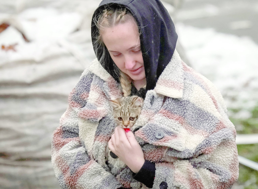 A local resident carries a kitten found in her flat in a residential building destroyed by a Russian missile attack in the town of Vyshhorod, near Kyiv, Ukraine, on Thursday. -- Reuters