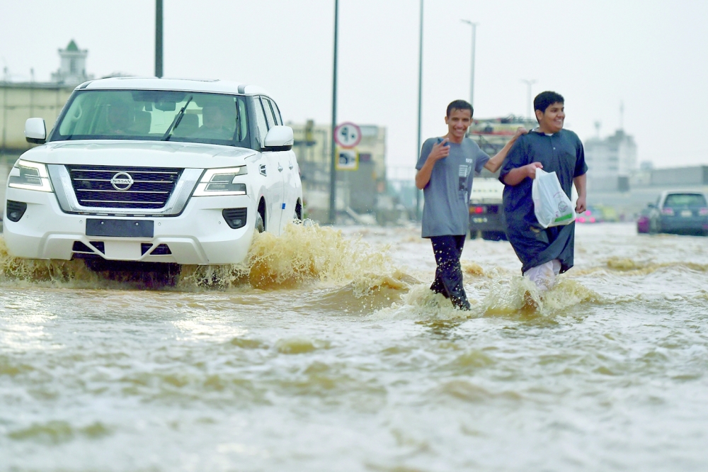 Men walk in a flooded street following heavy rains in the Saudi coastal city of Jeddah on Thursday. — AFP 
