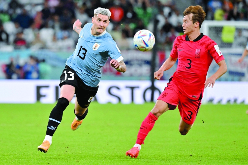 Uruguay's defender #13 Guillermo Varela and South Korea's defender #03 Kim Jin-su run with the ball during the Qatar 2022 World Cup Group H football match between Uruguay and South Korea at the Education City Stadium in Al-Rayyan, west of Doha on November 24, 2022. (Photo by JUNG Yeon-je / AFP)

