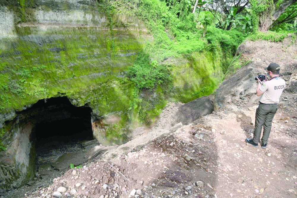 A bureau of corrections officer takes photos of a large pit near the official quarters of the country's prisons chief at the New Bilibid Prison facility in Muntinlupa City. -- AFP
