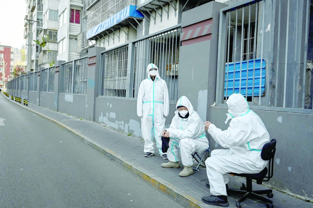 People in personal protective equipment (PPE) are seen at a residential compound under lockdown due to Covid-19 coronavirus restrictions in Beijing. -- AFP