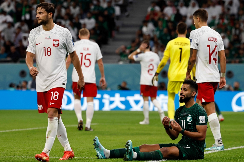 Saudi Arabia's forward #11 Saleh Al-Shehri (R) reacts as Poland's defender #18 Bartosz Bereszynski (L) walks past Saudi Arabia's forward Saleh Al-Shehri during the Qatar 2022 World Cup Group C football match between Poland and Saudi Arabia at the Education City Stadium in Al-Rayyan, west of Doha on November 26, 2022. (Photo by Khaled DESOUKI / AFP)