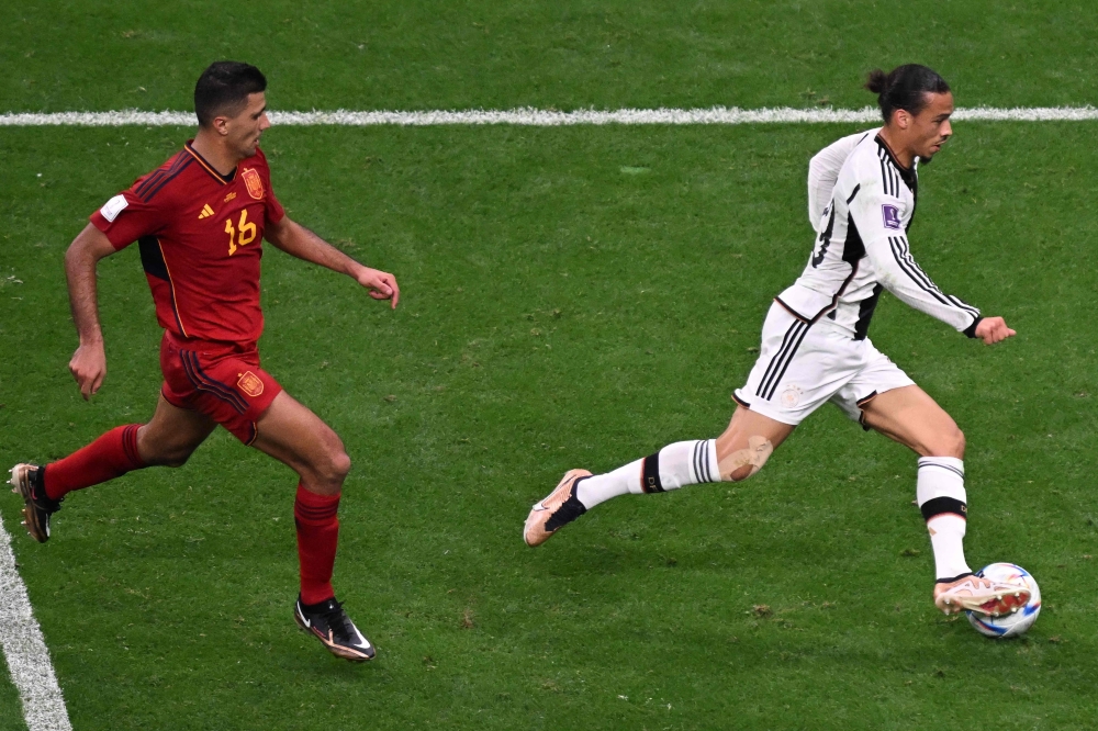 Germany's forward #19 Leroy Sane is marked by Spain's midfielder #16 Rodri during the Qatar 2022 World Cup Group E football match 