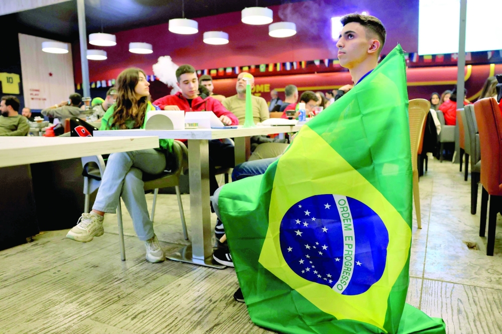 Lebanese watch a streaming broadcast of the FIFA World Cup 2022 group G soccer match between Brazil and Switzerland, at a café-restaurant in the area of Sabtiyeh, north of Beirut, on Monday. Lebanon being hit hard by the economic crisis, the country did not obtain the rights to broadcast the 2022 World Cup this year, depriving Lebanese fans of the World Cup. — AFP
 (Photo by JOSEPH EID / AFP)

