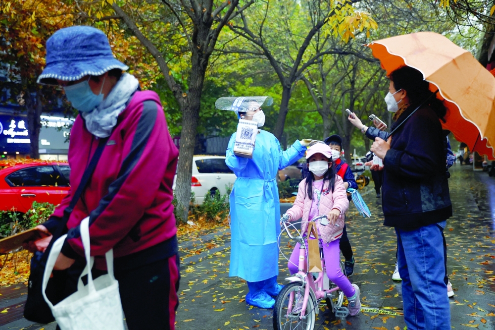 An elderly person scans a QR code at a testing site for Covid-19 in Beijing. -- AFP