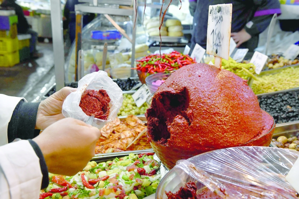 A shopkeeper scoops Tunisian Harissa to serve customers at the central market of the capital Tunis on Thursday. — AFP