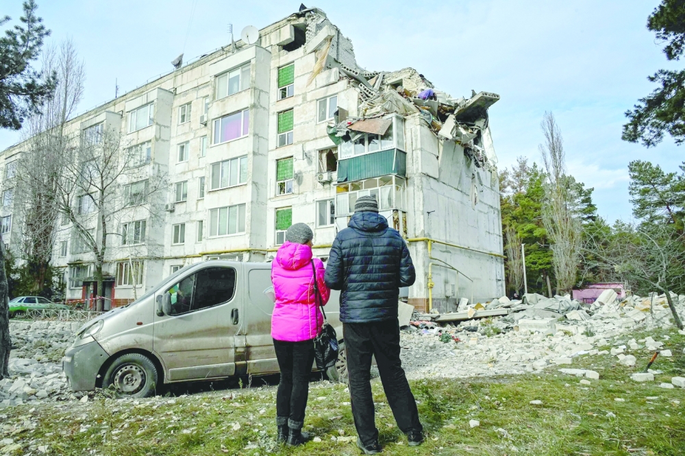 Local residents look at a residential building damaged by a missile attack in the village of Kluhyno-Bashkyrivka, Kharkiv region. -- AFP