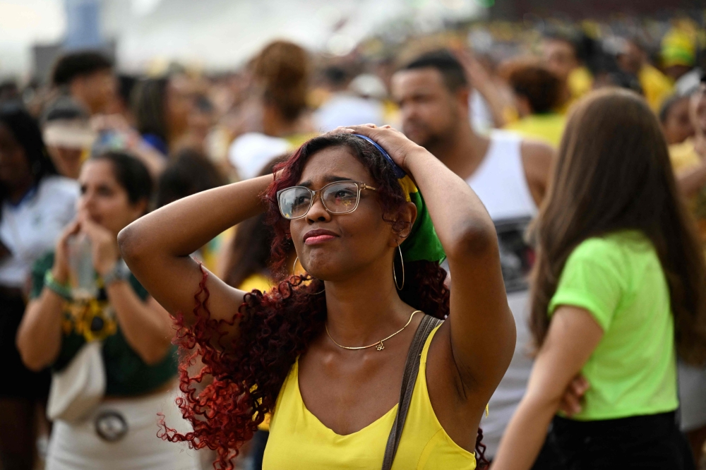 A fan of Brazil reacts while watching the live broadcast of the Qatar 2022 World Cup Group G football match between Cameroon and Brazil at the FIFA FanFest in Copacabana beach, Rio de Janeiro, Brazil, on December 2, 2022. 
