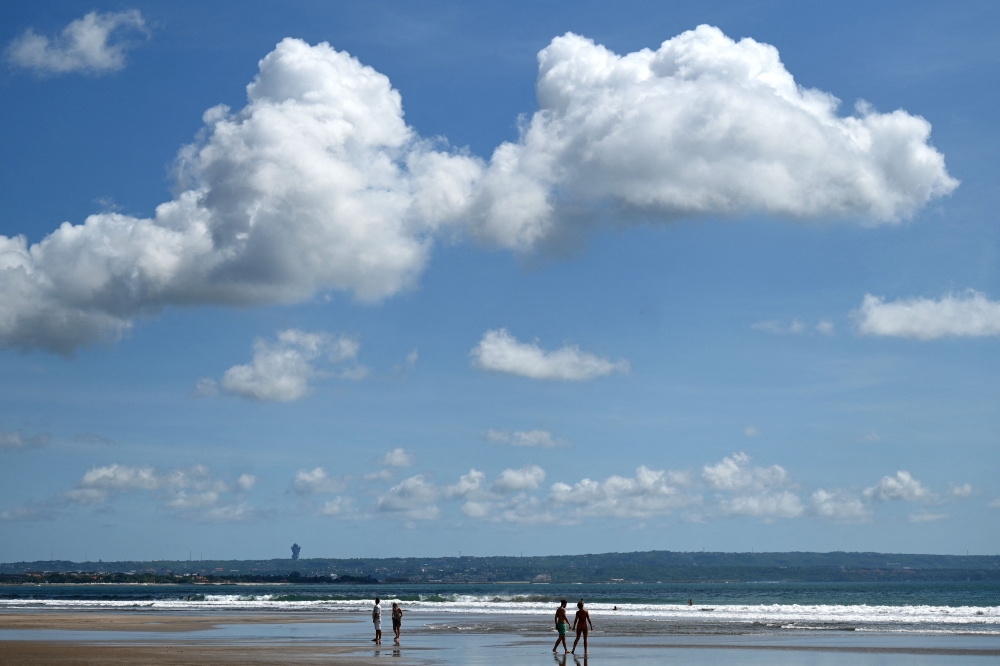 Foreign tourists walk on a beach in Seminyak, Badung regency on Indonesia resort island of Bali, on December 7, 2022. 