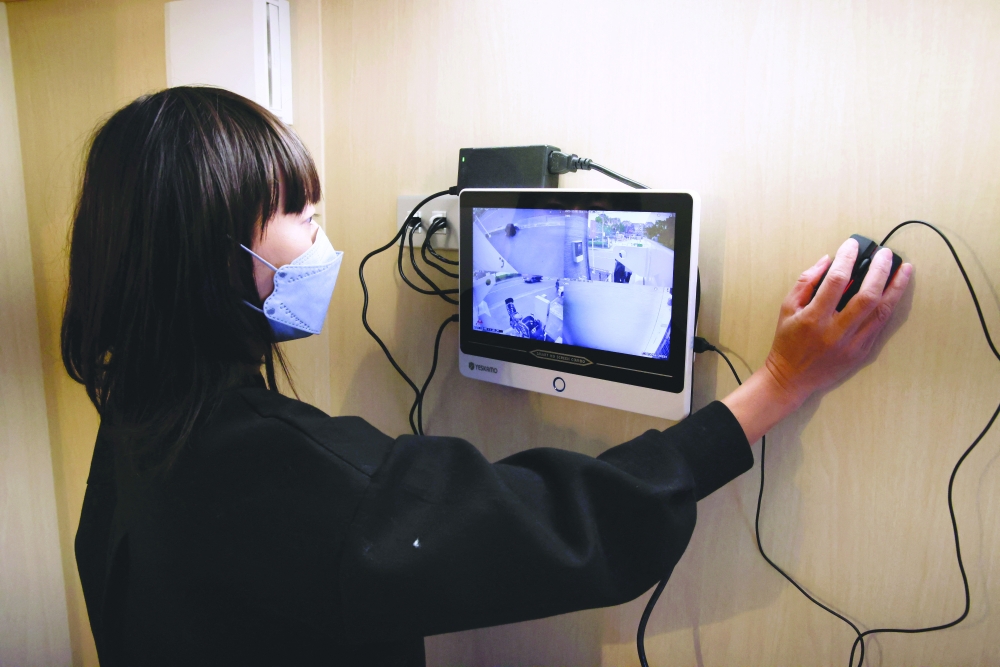 Megumi Morohoshi, a Japanese mother of three, demonstrates the external surveillance system of her family's newly installed bomb shelter in Saitama, Japan. - Reuters