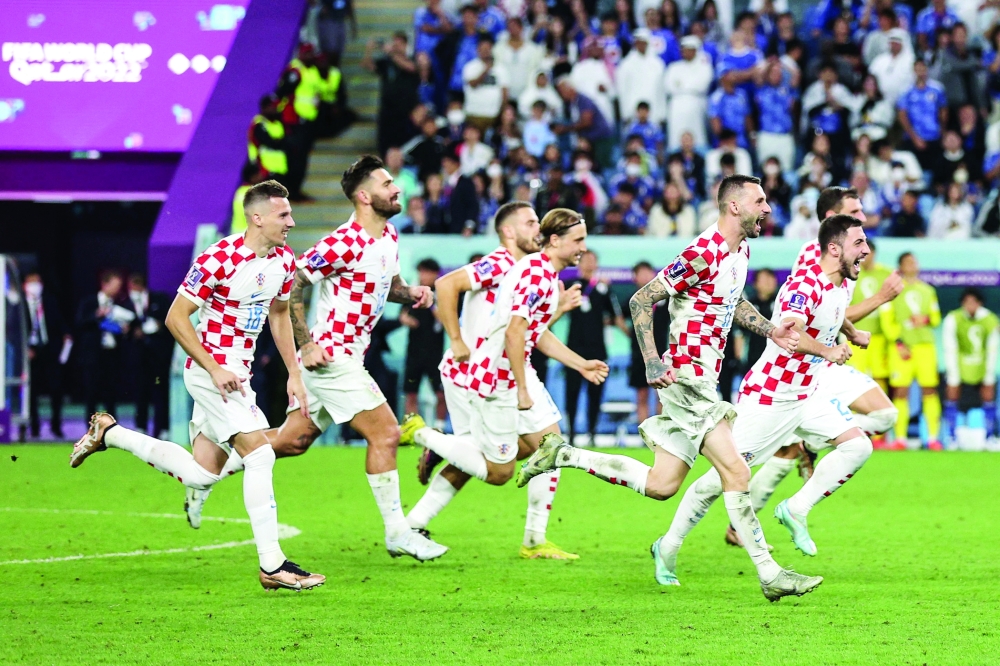 Croatia's players celebrate their win in the Qatar 2022 World Cup round of 16 football match between Japan and Croatia at the Al-Janoub Stadium in Al-Wakrah, south of Doha on December 5, 2022. (Photo by ADRIAN DENNIS / AFP)

