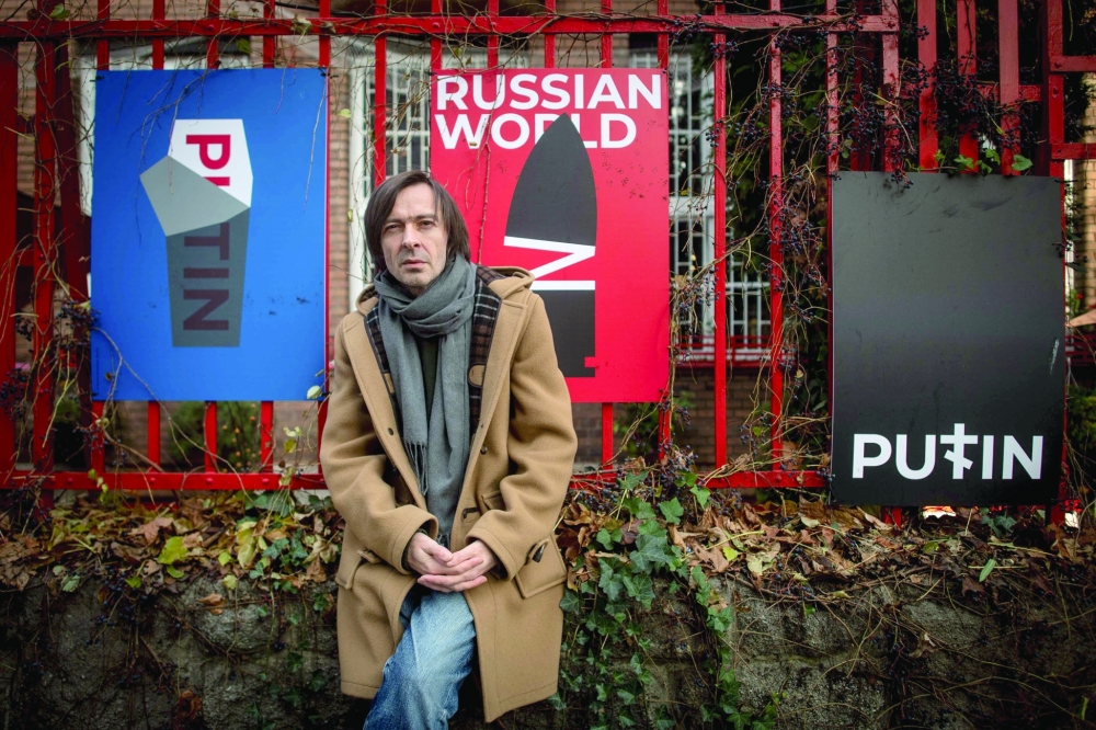 Ukrainian graphic designer Mykola Kovalenko poses during a photo session in front of his posters in downtown Bratislava, Slovakia. — AFP