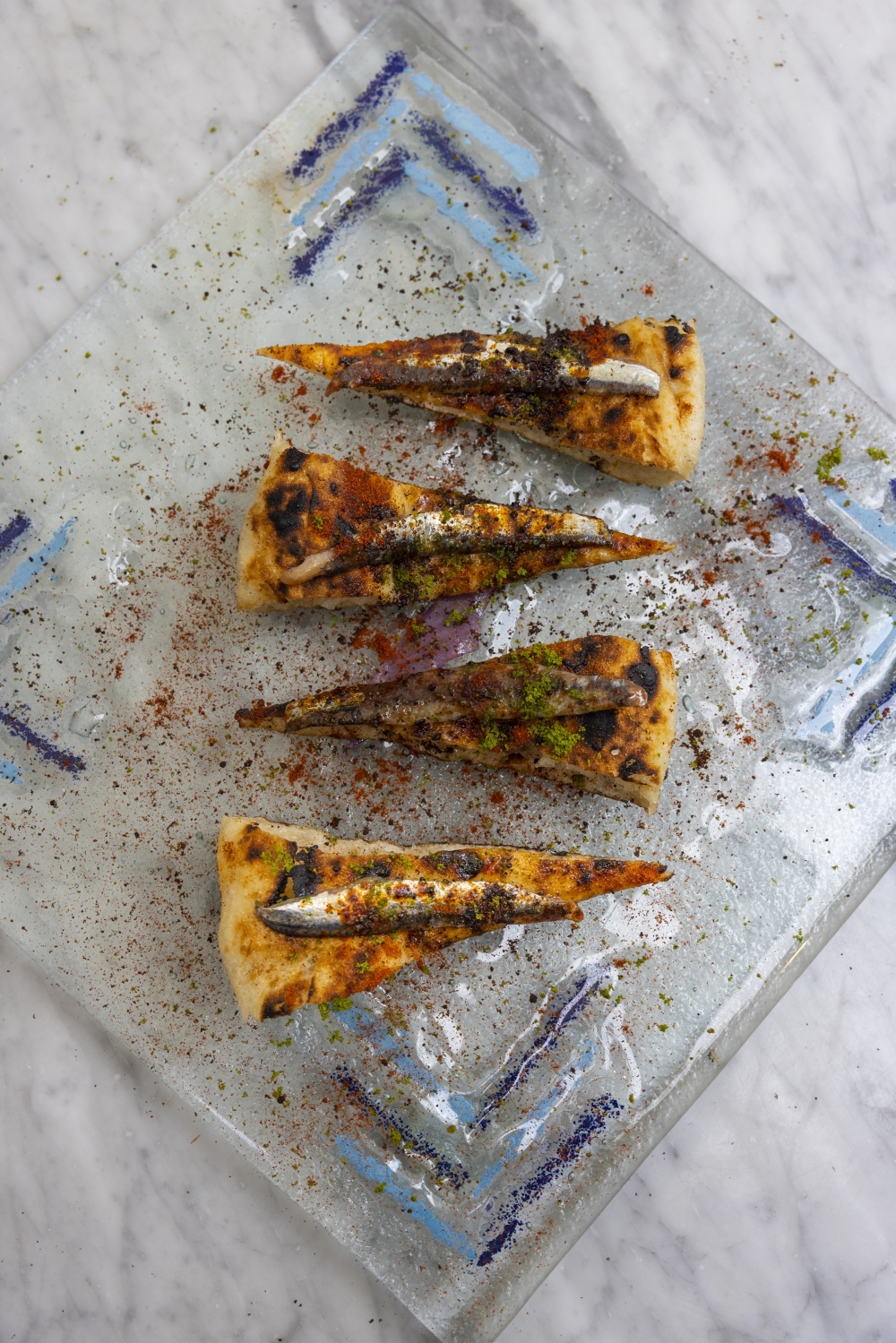 Wedges of pizza with anchovies and butter sprinkled with dried powders of black olives and pesto at the Concettina ai Tre Santi pizzeria in the Sanit