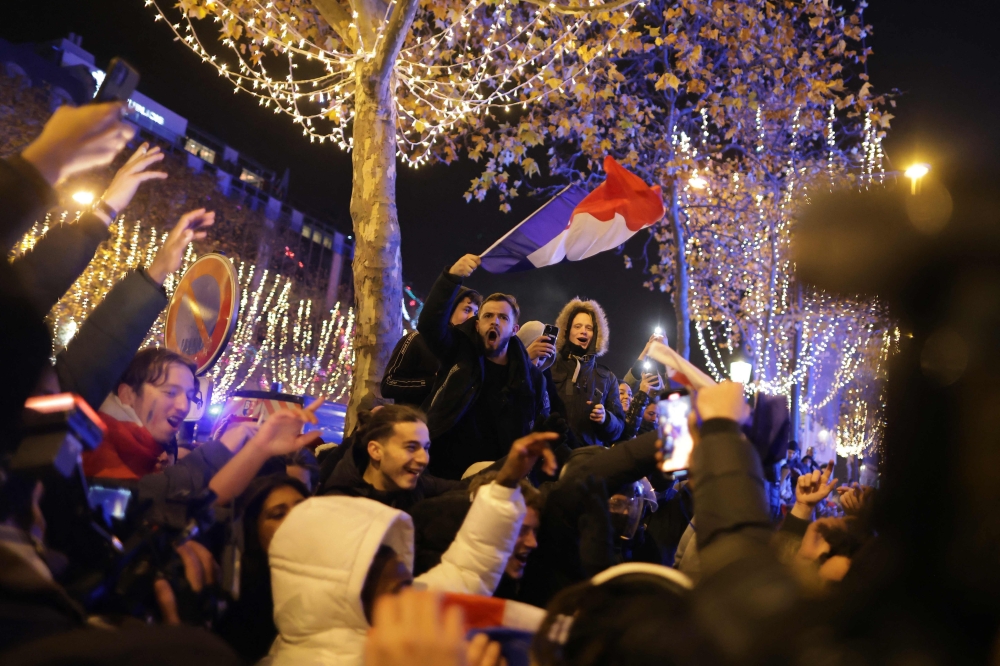  A football fan holds the French flag as he celebrates after France's victory over Morocco in the Qatar 2022 World Cup semi-final, on the Champs-Elysees in Paris on December 14, 2022.