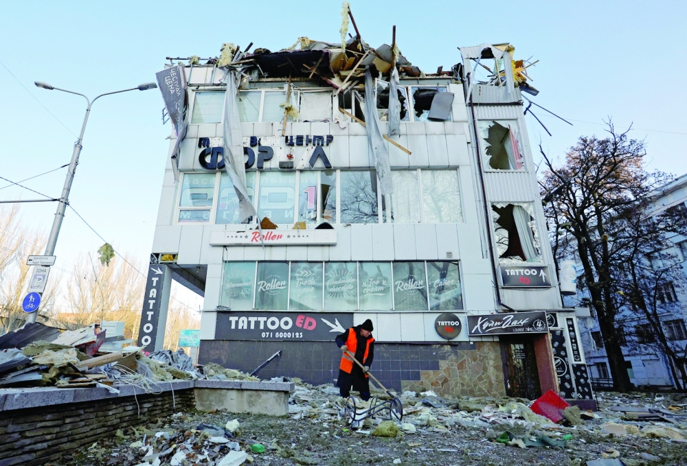A worker removes debris in front of an office building damaged by shelling in Donetsk. -- Reuters

