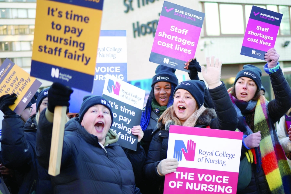 NHS nurses display signs as they strike outside St Thomas' Hospital in London. -- Reuters
