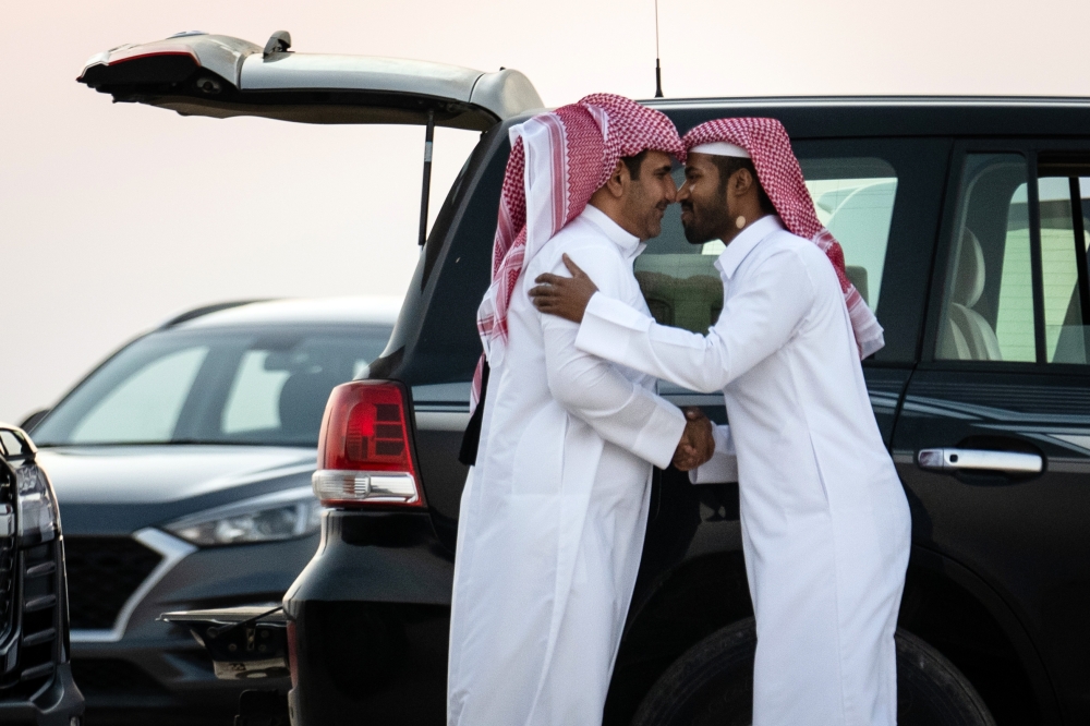 Qatari men greet each other by rubbing noses as they gather to train their falcons for hunting competitions outside of Al Khor, Qatar, on Dec. 3, 2022. (Erin Schaff/The New York Times)