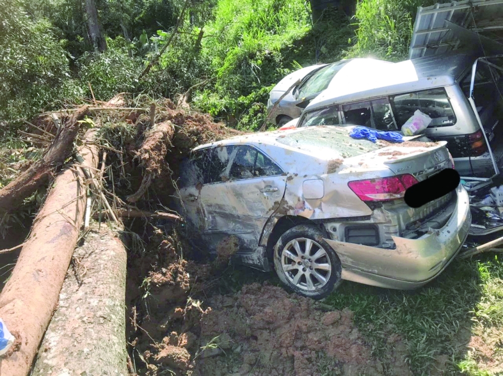 Damaged cars are seen amongst the debris during a rescue and evacuation operation following a landslide at a campsite in Batang Kali, Selangor state. - Reuters