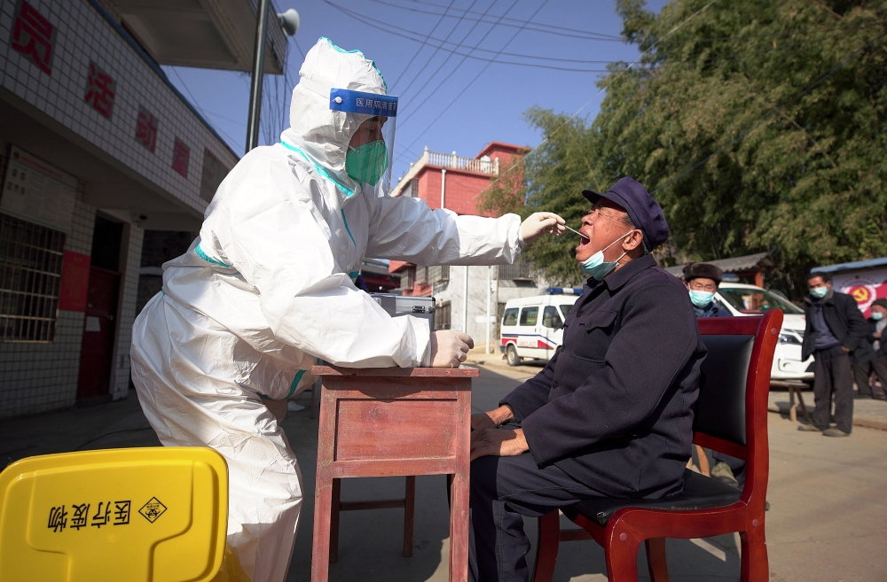 A health worker takes a swab sample from a man to be tested for the Covid-19 coronavirus in Danzhai