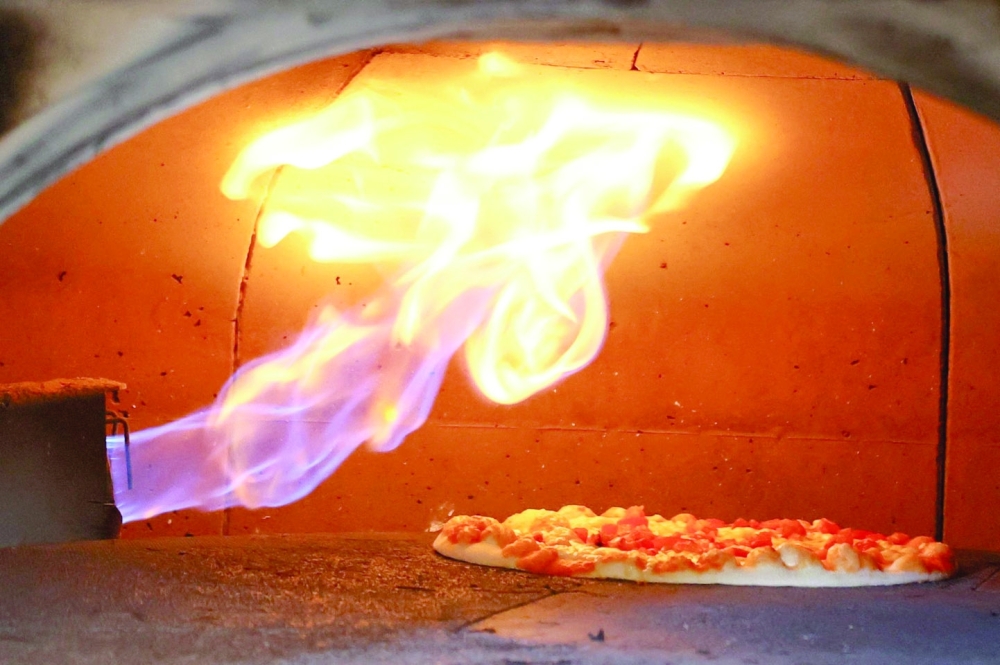 A pizza is baked in a traditional Italian pizza oven fired with natural gas, at a restaurant in Bonn, Germany. -- Reuters