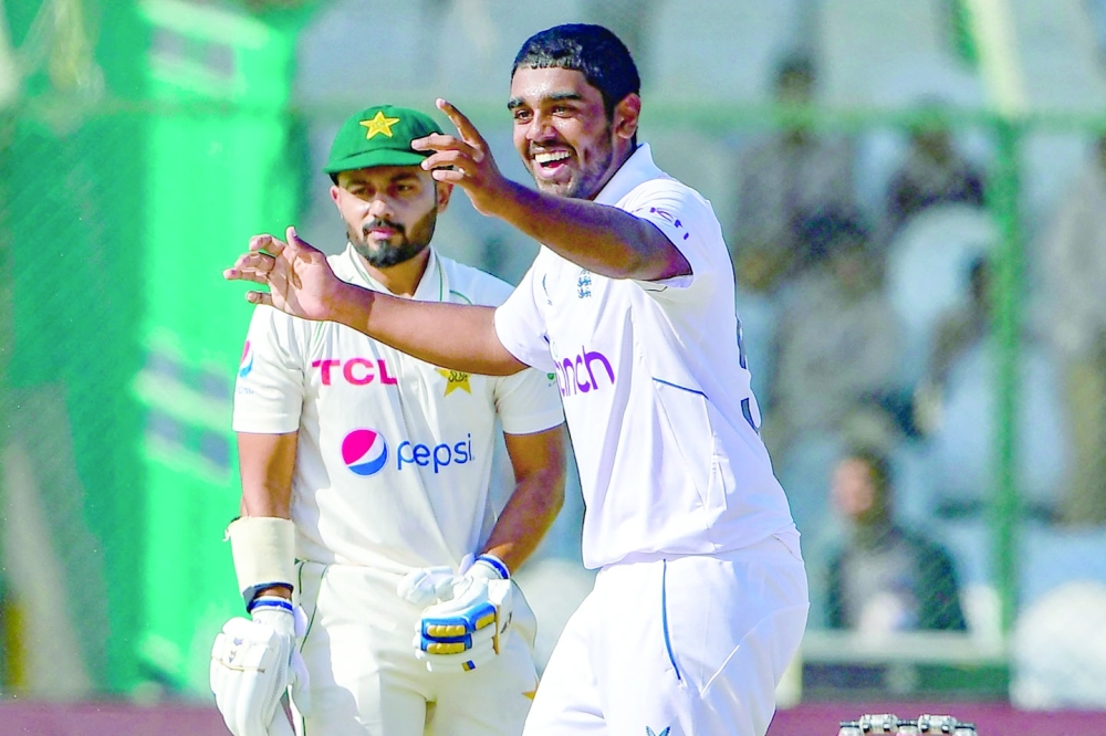 England's Rehan Ahmed (R) celebrates after the dismissal of Pakistan's Saud Shakeel (L) during the first day of the third cricket Test match between Pakistan and England at the National Stadium in Karachi on December 17, 2022.  (Photo by Asif HASSAN / AFP)

