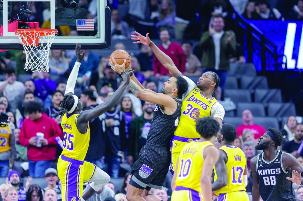 December 21, 2022; Sacramento, California, USA; Sacramento Kings forward Trey Lyles (41) shoots the ball against Los Angeles Lakers centre Damian Jones (30) and forward Wenyen Gabriel (35) during the fourth quarter at Golden 1 Center. Mandatory Credit: Sergio Estrada-USA TODAY Sports