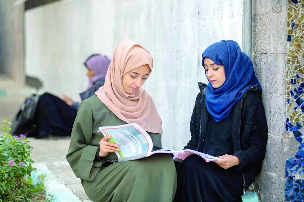 Women read books at a university in Taiz. — AFP