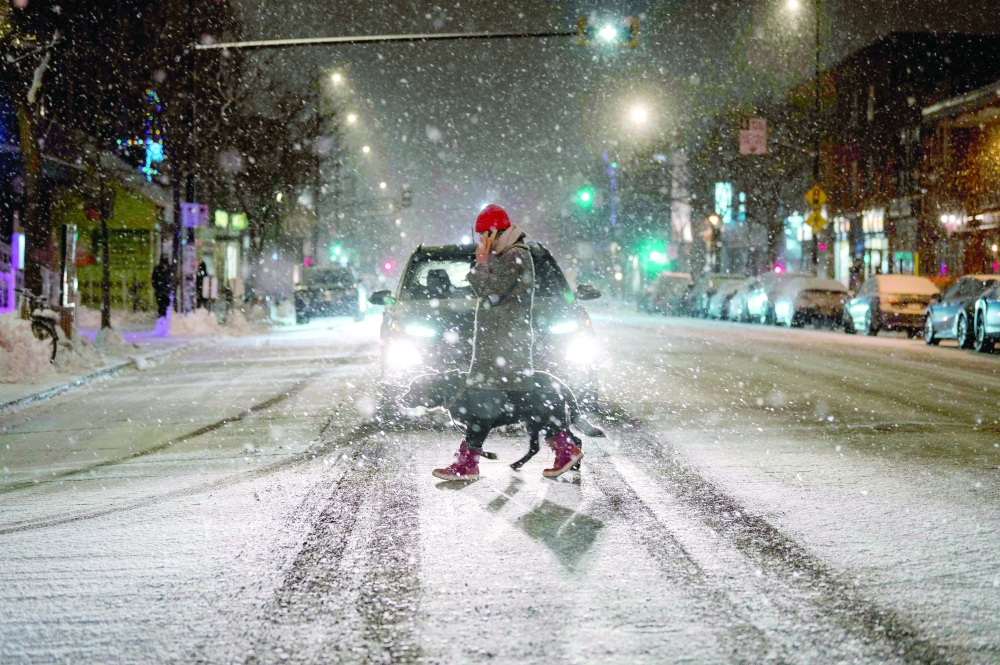 A person crosses a street in the Mile End, a borough in Montreal, Quebec, Canada, as the snow comes down. A 'once-in-a-generation' winter storm with temperatures as low as - 40 degrees Fahrenheit has caused Christmas travel chaos in the United States with thousands of flights cancelled and major highways closed. -- AFP