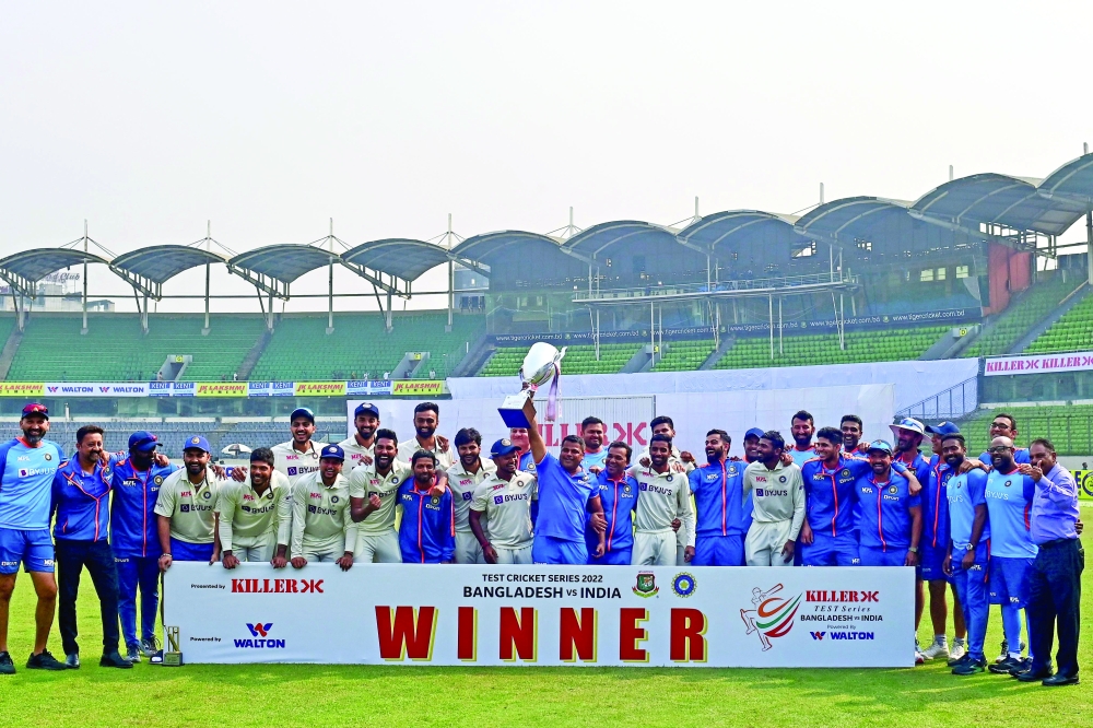 India痴 cricket team poses for a photo as they hold the tournament trophy after winning on the fourth day of the second cricket Test match between Bangladesh and India at the Sher-e-Bangla National Cricket Stadium in Dhaka on December 25, 2022.  (Photo by Munir uz ZAMAN / AFP)

