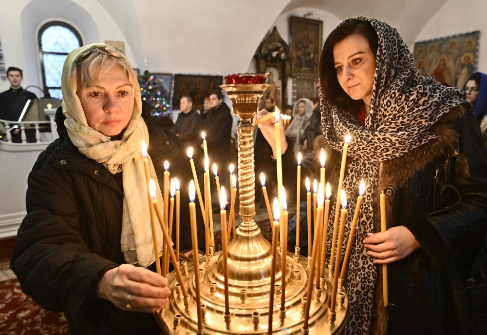 Women light candles during the Christmas service in a church of the Orthodox Church of Ukraine in Kyiv on Sunday, amid the Russian invasion of Ukraine. — AFP 